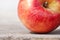 Red juicy solid fruit apple under sunlight on a blackboard against a gray wall. Concept of a natural nutrition organic food