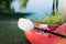 Red kayak and white paddle pointed towards water