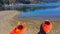 Red kayaks beached in foreground on a sandy beach. At the rivers edge. Curved waters reflect tree line.