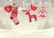 Red knitted christmas stocking with some scandinavian traditional decorations hanging on branches in front of simple