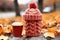 Red knitted cup cozy and cup of coffee of yellow leaves background. Generative AI