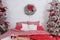Red knitted cups of tea staying on wooden tray lies on bed. Winter holiday morning, cozy room. White Bedroom interior with checker