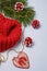 Red knitted snood, pine branch, red painted cones, wooden heart shaped toy with golden beads on light background. Christmas