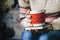 Red Knitted woolen cup with heart pattern in female hands.