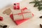 Red and kraft christmas gifts surrounded with pine cones, leaves and twine on a wooden table