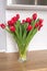 Red kung fu tulips stand in a glass vase on the table. Bouquet of flowers