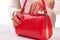 Red lacquered handbag in female hands.