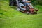 Red Lawn mower cutting grass. Gardening process of lawn mowing