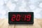 Red led light illuminated number 2019 on digital electric alarm clock screen on brown wood table top