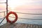 Red lifebelt on wooden pier on background of seascape at dawn.