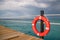 Red lifebuoy on the dock against the background of the stormy sky over the sea