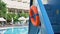 Red lifebuoy hangs on large plastic slide stairs by pool