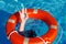 Red lifebuoy on the surface of the water in the pool and the hands of a man grabbing it