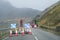 Red light at road works and traffic cones with safety sign at rural isolated mountain scene