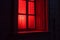 red light from the window. the red window shines mystically at night. mysterious red window