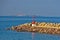 Red lighthouse at entrance to small ferry harbor in Sardinia