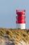 Red lighthouse on Helgoland Duene island in blue sky, sand beach