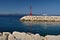 Red lighthouse in port with stones and white bench