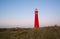 Red lighthouse at sunset on island coast