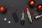 Red lipstick, Christmas balls, confetti on black background top view flat lay copy space. Professional Makeup and Beauty.