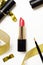 Red lipstick and lip brush top view composition. Makeup accessories and golden decorations on white background. Beauty industry