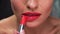 Red lipstick. Woman applying lipstick on full lip closeup