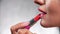 Red lipstick. Woman applying lipstick on full lip closeup