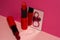 Red lipsticks and small mirror on bright pink background. Holiday is March eighth, day of women and spring.