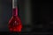 Red liquid in a round bottomed flask on a black granite table in dark background