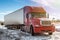 Red long-distance bonnet truck with a white semitrailer at winter