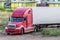 Red long-distance truck with a white semitrailer in the countryside