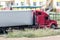 Red long-distance truck with a white semitrailer in the countryside