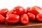 Red long tomatoes on a wooden board and white background