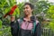 Red loryperching on the man hand. Asian handsome tenager with a parrot in a tropical bird park. Eos Bornea is a species
