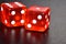 Red luminescent casino dice on black reflecting background