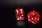 Red luminescent casino dice on black reflecting background