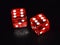 Red luminescent casino dice on black reflecting background