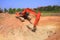 Red machinery digging red soil is big hole on blue sky