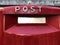 Red mailbox on a brick wall with Post text on it close-up. mailing concept