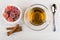 Red marmalade in bowl, tea, cinnamon and teaspoon on table