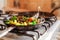 Red meat with vegetables in old fry pan on a cooker.