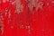 Red metal background with peeling blistering paint