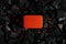 Red metal box on charcoal back. Copy space in a rectangle on a background of hot coals