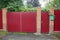 Red metal gate and door and part of a fence in the street