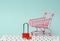 A red metal padlock stands on the keyboard and behind a miniature shopping cart, blue background