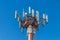 A red metal tower with white cellular antennas against a blue sky background