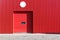 Red metal warehouse wall with closed roller shutter gate
