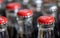 Red metals caps on the top of retro style coca cola bottles carrying the message `Please recycle me`.