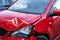 Red mini car severely damaged after traffic accident with deployed airbag