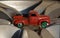 Red model car pickup with green wheels painted by small children while their car game lies on real silver car wheels